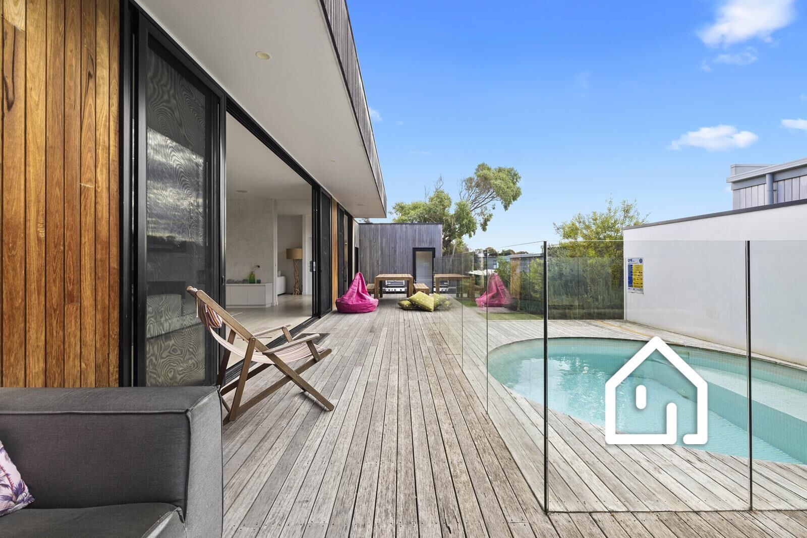 Eine moderne Außenterrasse mit Pool, Holzboden und Sitzbereichen.