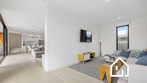 A modern living room with a sofa, coffee table, and a TV mounted on the wall.