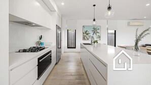 A modern kitchen with white cabinetry, a central island, a gas stove, and pendant lighting.