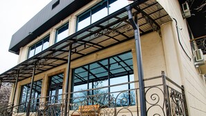 Un edificio de varios pisos con un balcón que cuenta con barandillas de metal ornamentadas y ventanas amplias.