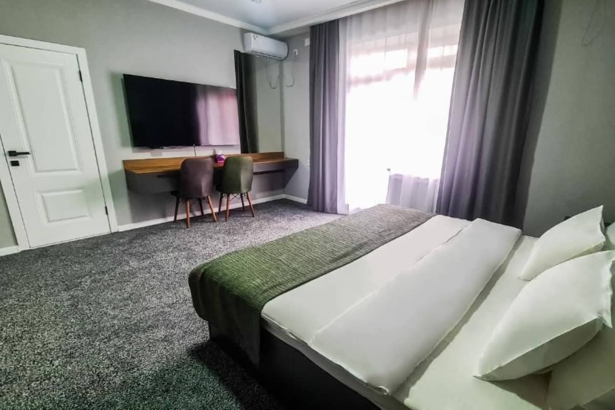 A hotel room with a bed, a desk, a chair, and a TV.