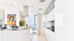 Une cuisine moderne avec des meubles blancs, une grande fenêtre et une vue sur la mer.