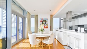 Une cuisine moderne avec des meubles blancs, un îlot central et un coin repas comprenant une table et des chaises blanches.