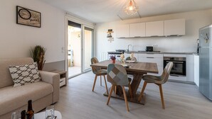 Une cuisine moderne avec des meubles blancs, une table à manger avec des chaises et un luminaire suspendu.