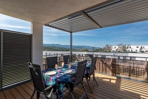 Un espace extérieur abrité, aménagé pour les repas, avec une table pour quatre personnes, offrant une vue sur un paysage pittoresque.