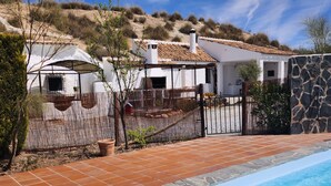 Vista de una piscina junto a una casa con patio de baldosas, alberca y pared de piedra.