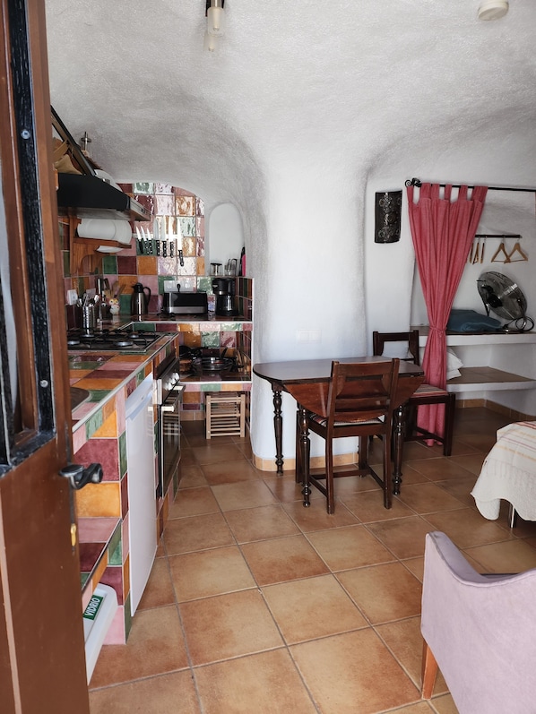 Cocina compacta con comedor, destacando un salpicadero de azulejos, armarios de madera y una pequeña mesa de comedor con sillas.