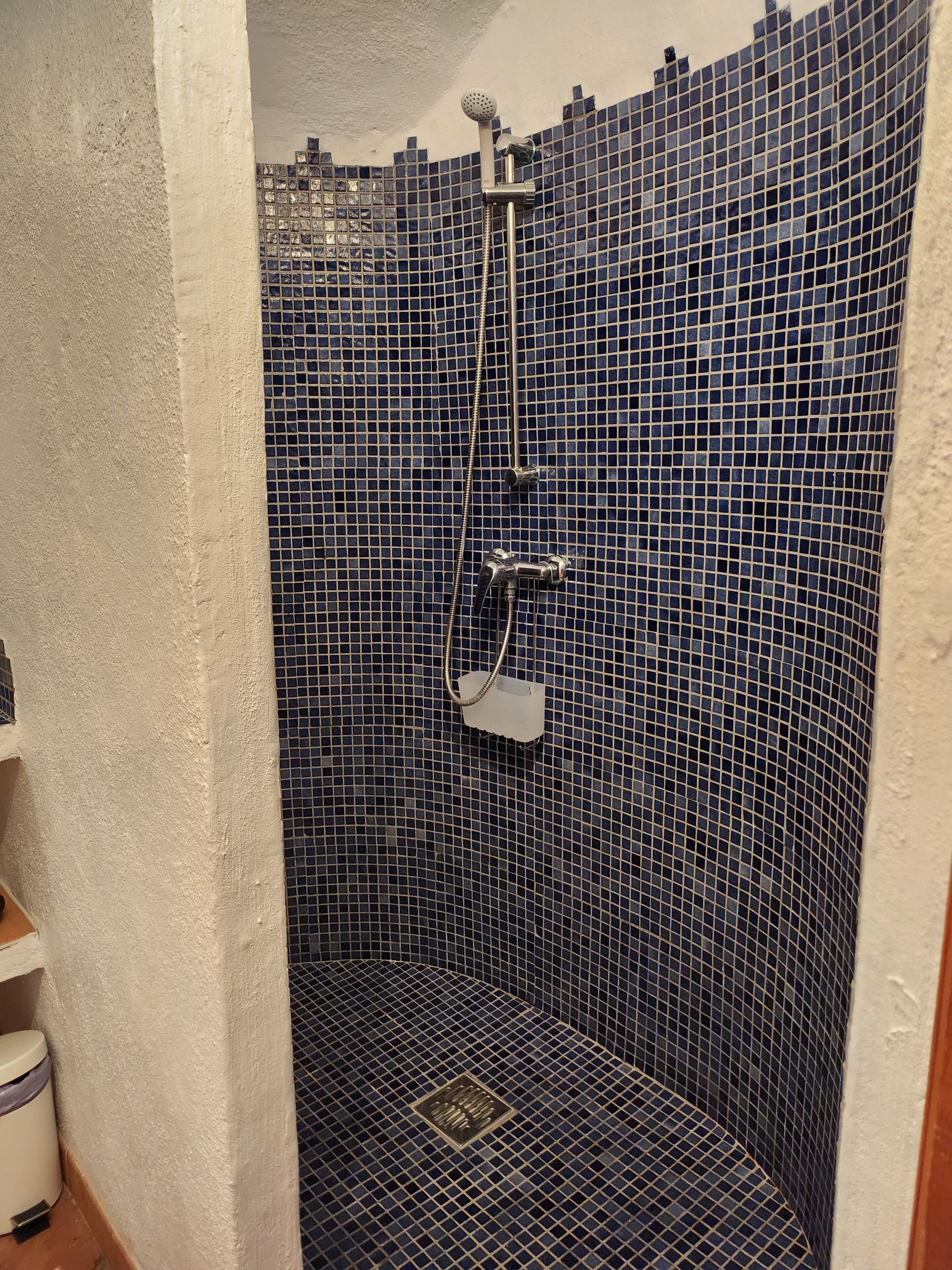 Un baño pequeño con azulejos, ducha de mano y grifo de pared.