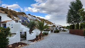 Una hilera de casas blancas con paneles solares, un camino de grava y una palmera.
