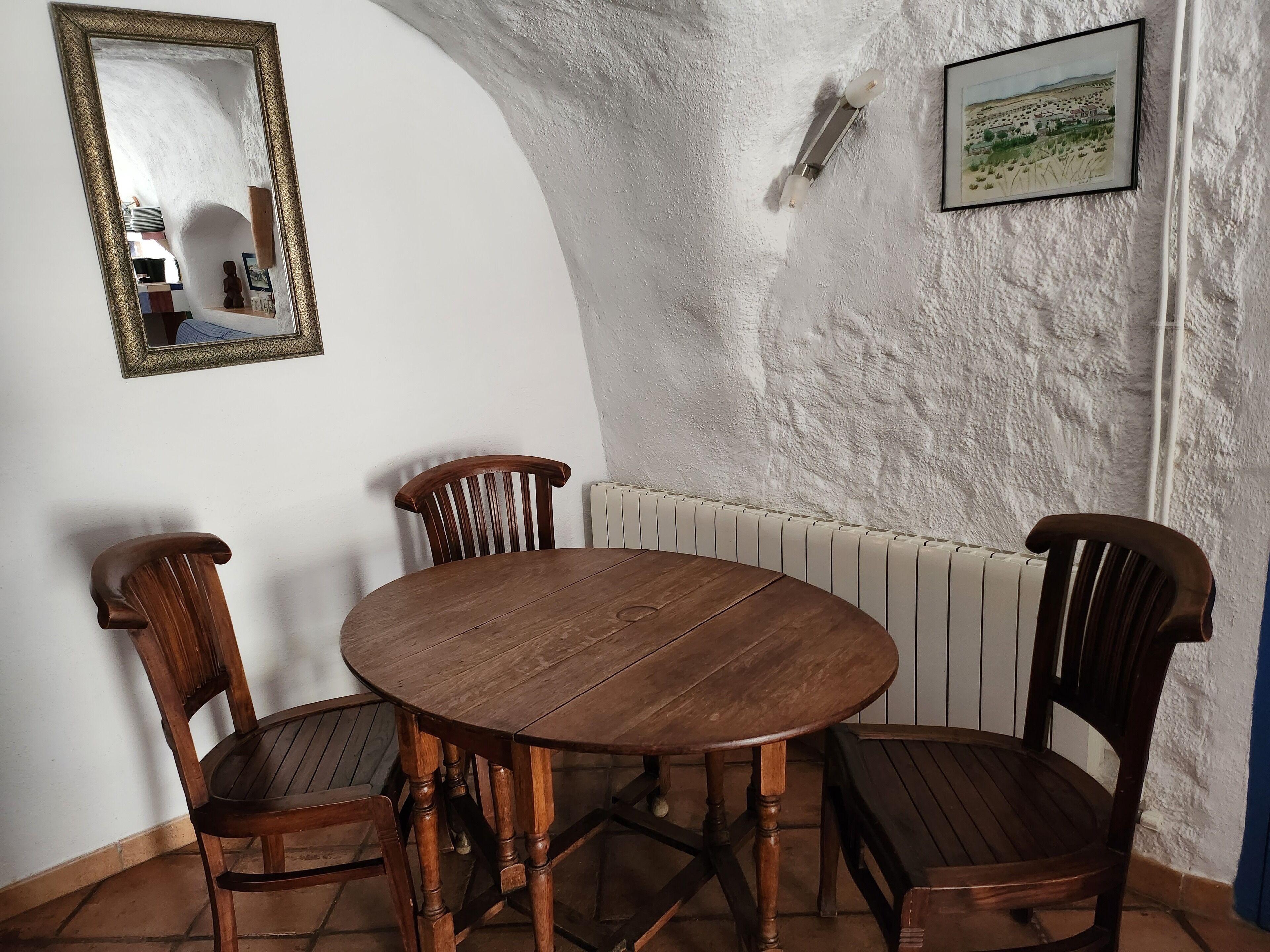 A dining area with a round wooden table and four wooden chairs.