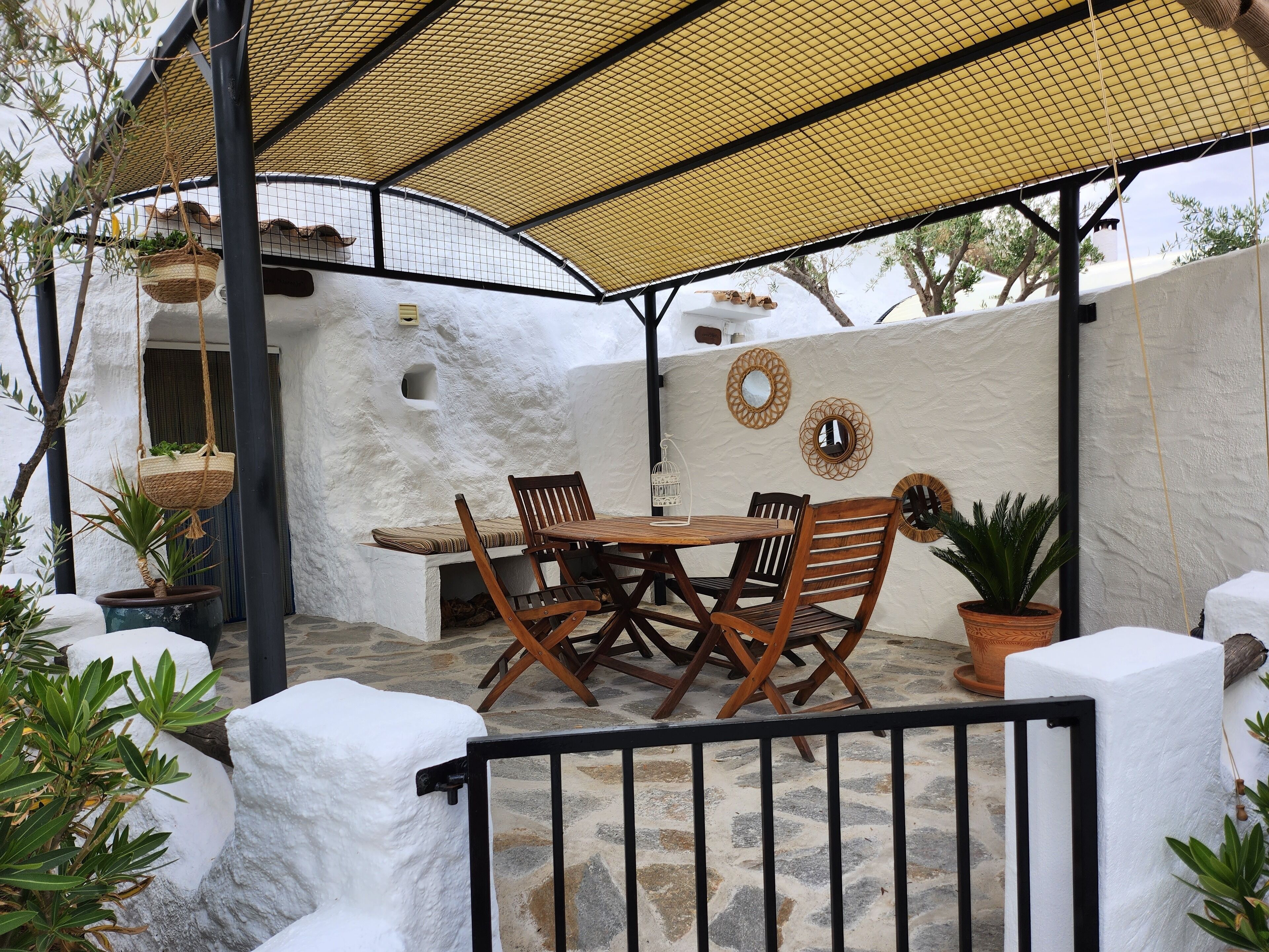 An outdoor patio with a table and chairs, surrounded by white walls and potted plants.