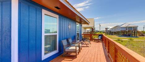 A wooden deck with outdoor seating, a large window, and a view of a playground.