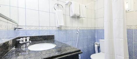Et badeværelse med vask i marmor, hvid toilet og blå fliserede vægge.