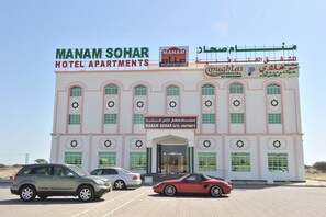 A building with signs for Manam Sohar Hotel Apartments and a restaurant. - Manam Sohar Hotel Apartments (Sohar)