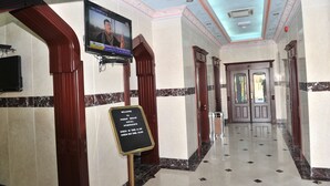 A hotel lobby with a television mounted on the wall, a check-in sign, and a marble floor. - Manam Sohar Hotel Apartments (Sohar)