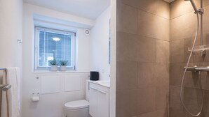 Une salle de bain comprenant des toilettes, un lavabo, une fenêtre et une douche.