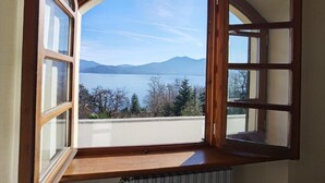 A room with a large arched window overlooking a lake and mountains. - Villa Schaake Lago Maggiore 100m vom Strand (Gonte)