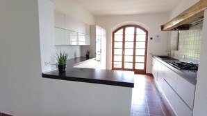 A modern kitchen with white cabinets, a black countertop, and a tiled floor. There are two potted plants on the counter. - Villa Schaake Lago Maggiore 100m vom Strand (Gonte)