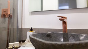 A bathroom with a stone basin, a mirror, and toiletries on the counter. - Liferooms b&b (Ischia)