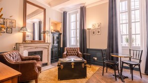 Ein gemütliches Wohnzimmer mit Kamin, Ledersessel und einem alten Truhenkoffer.