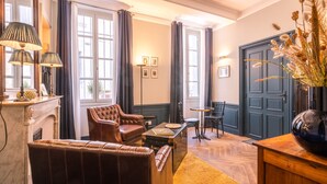 Ein Zimmer mit Ledersesseln, einem kleinen runden Tisch, einem Kamin und einer dunklen Holztür.