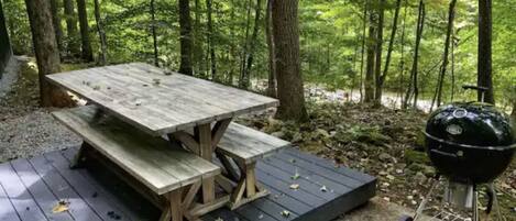 A picnic table with benches in a forested area.