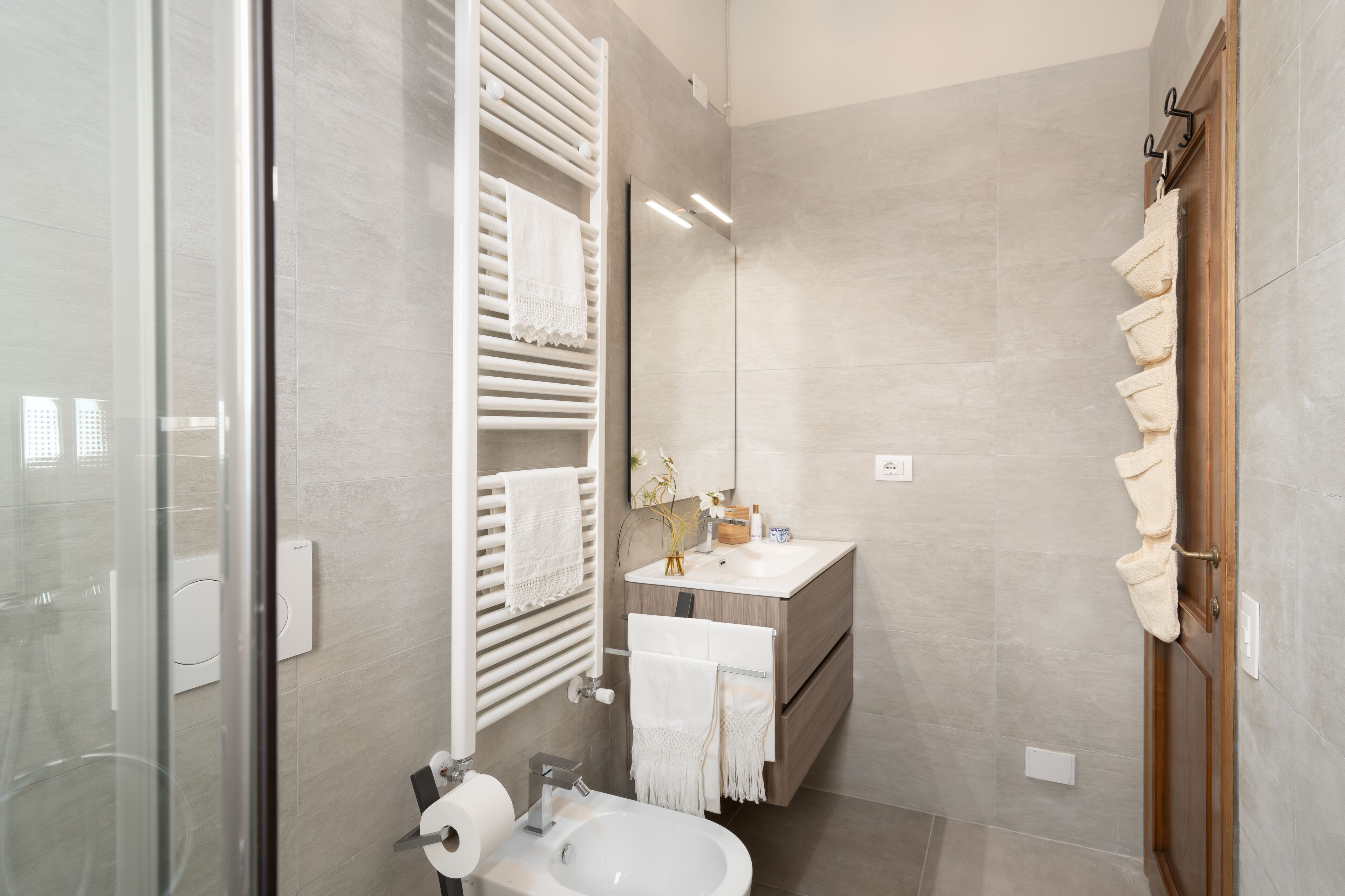 A modern bathroom with a glass shower enclosure, a vanity with a sink, and a towel rack.