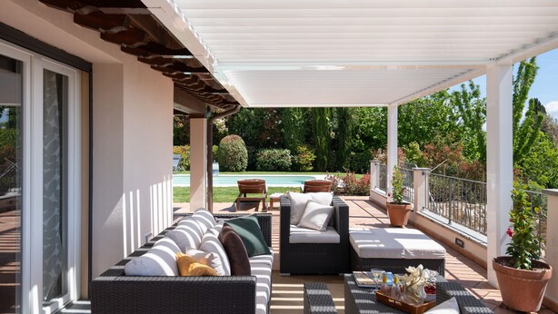 A covered outdoor seating area with wicker furniture, a pool, and potted plants. - La Capannina Di Pillo (Gambassi Terme)