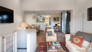 A living room with a sofa, a coffee table, and a television. There is a staircase leading to an upper level. - La Capannina Di Pillo (Gambassi Terme)