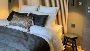 A modern bedroom with a large bed, a small stool, and vertical wooden slats on the wall. - Luxurious villa close to Colmar, Kaysersberg... (Labaroche)
