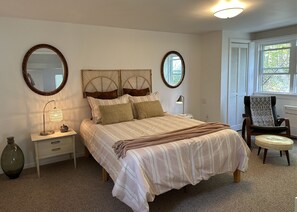A bedroom with a bed, bedside tables, a chair, and two mirrors. - Lake House (Trumansburg)