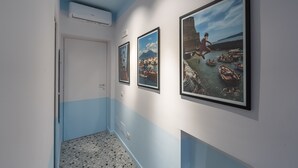 A hallway with three framed pictures on the wall, a door, and an air conditioning unit on the ceiling. - Teatro Toledo 272 (Naples)
