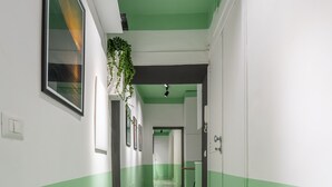 A hallway with green walls and a speckled floor, leading to a room with a bed and a window. - Teatro Toledo 272 (Naples)