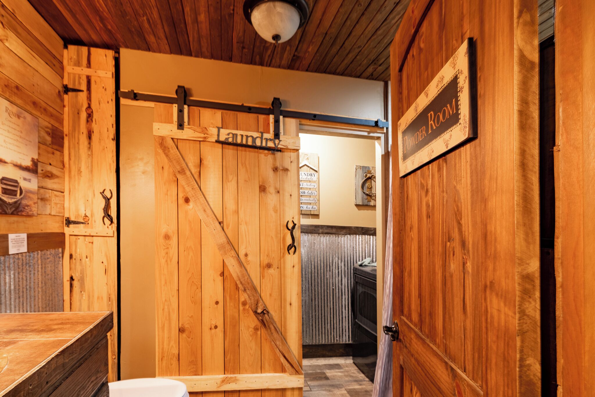 A wooden interior with a sliding door labeled "Laundry" and a sign for "Powder Room".