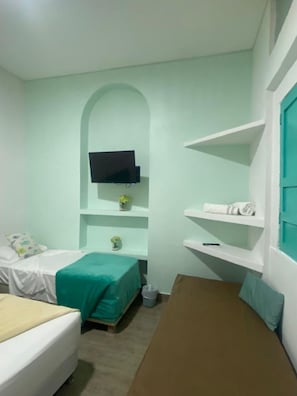 A bedroom with a bed, a desk, a TV mounted on the wall, and a small shelf with a plant. - 4cr-1m 4 Bedroom House In Getsemani With Air Conditioning And Wifi (Cartagena)