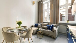 Ein modernes Wohnzimmer mit einem Glastisch, einem beigen Sofa und blauen Kissen.