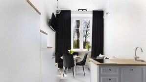 Eine moderne Küche mit Essbereich, mit einem großen Fenster mit Vorhängen, einem Esstisch mit Stühlen und einer Kücheninsel mit Spüle.
