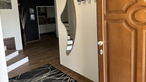 Een gang met een houten deur, een zwart-wit tapijt, een spiegel en een bord waarop 'HOME' staat.