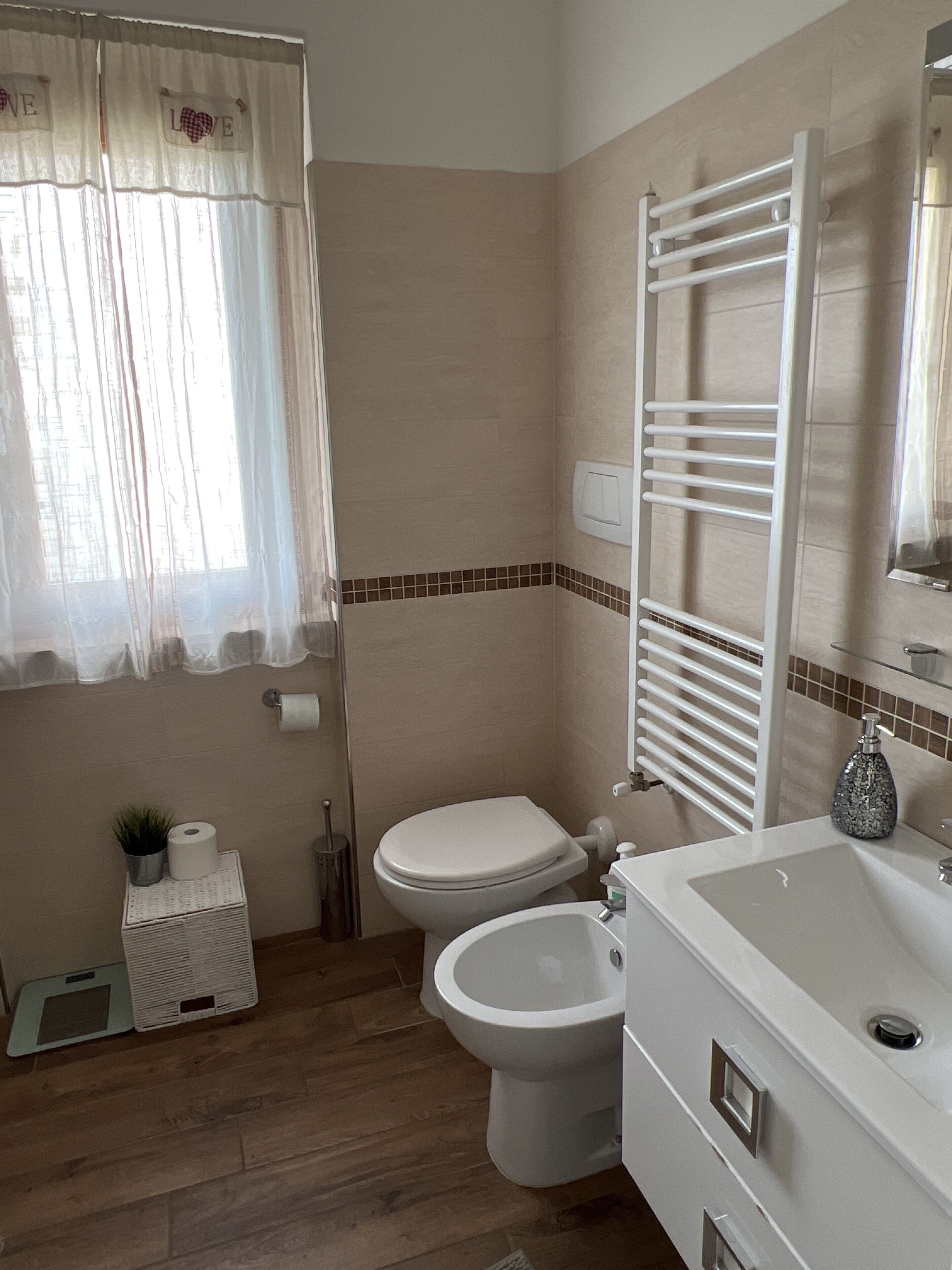 A bathroom with a toilet, bidet, sink, and towel rack.