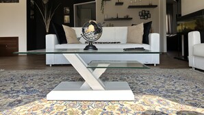 Een moderne woonkamer met een witte bank, een glazen salontafel en een decoratieve wereldbol.