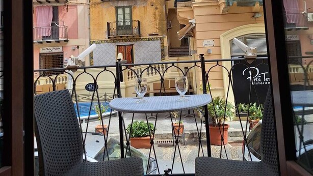 Un balcon avec deux fauteuils en osier, une petite table ronde et des plantes en pot.