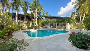 A swimming pool surrounded by palm trees and a building with a covered patio area. - "srvittinivillas Great / Family / Trip Team/ Caribbean Dr" (San Rafael del Yuma)