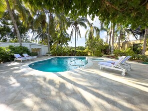 A swimming pool with lounge chairs, surrounded by palm trees and greenery. - "srvittinivillas Great / Family / Trip Team/ Caribbean Dr" (San Rafael del Yuma)