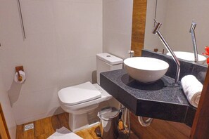 Un baño pequeño con inodoro blanco, lavamanos sobre encimera y espejo.