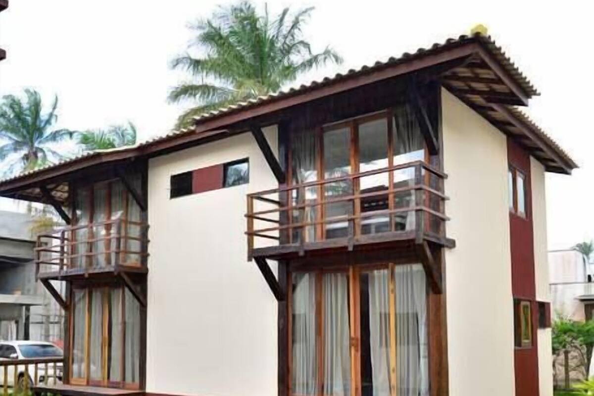 A two-story building with a swimming pool, wooden deck, and a covered patio area.