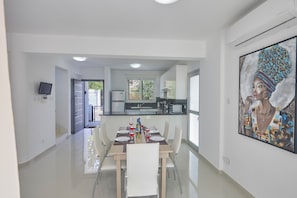 Enjoy meals with family and friends at this stylish dining area, featuring a long table for four and a beautiful abstract art piece.