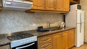 Une cuisine avec des meubles de rangement en bois, une cuisinière à gaz, un four à micro-ondes et un réfrigérateur.