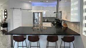 A modern kitchen with a large island, stainless steel appliances, and bar stools.