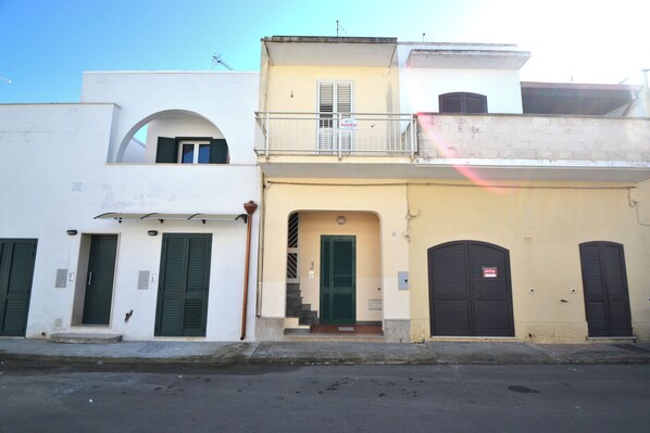 A row of buildings with a central archway, a balcony, and a staircase leading to an upper level. - Alba Two-room Air-conditioned Holiday Home for 4 Guests (Melendugno)