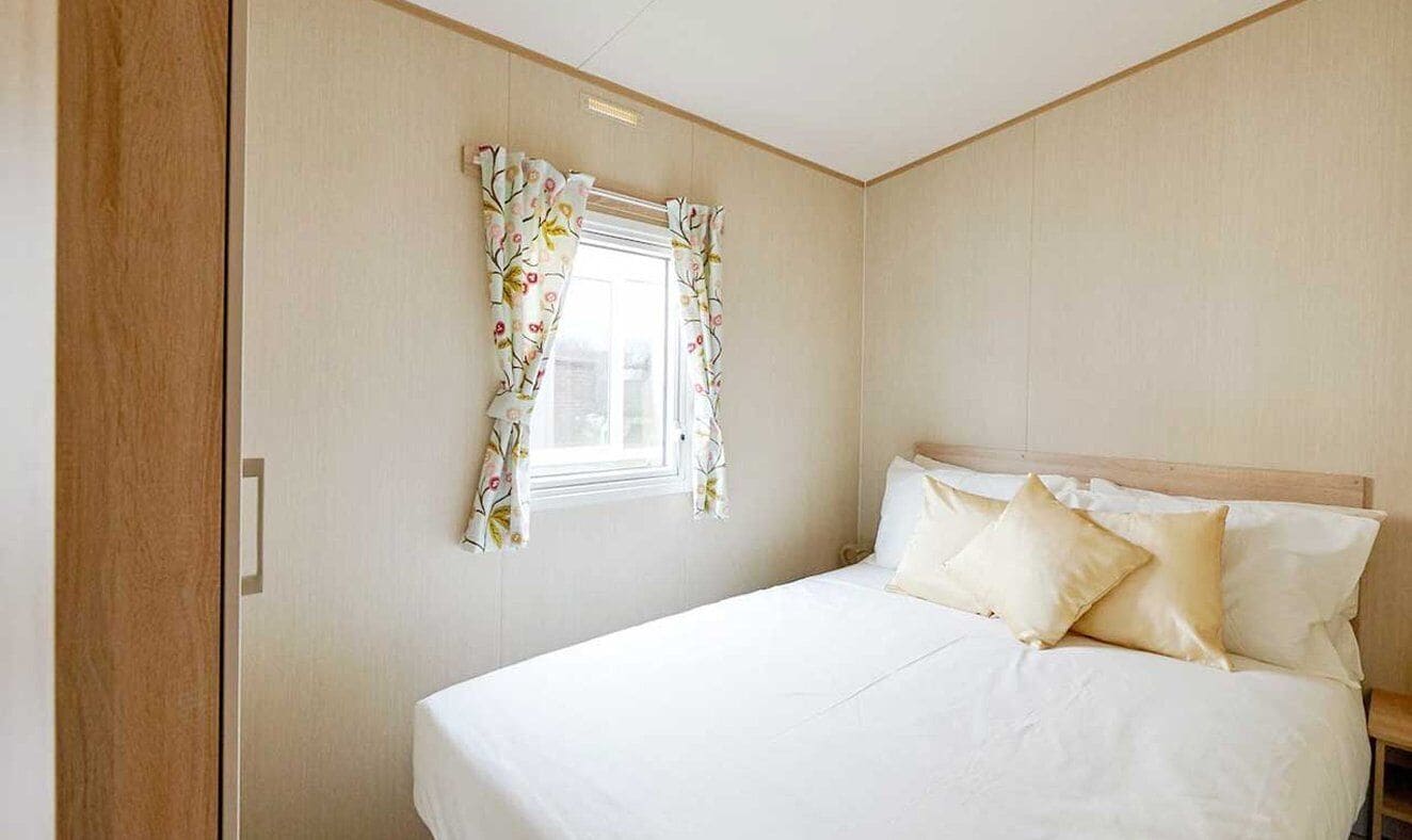 Un dormitorio con una cama, una ventana con cortinas florales y una puerta de madera.